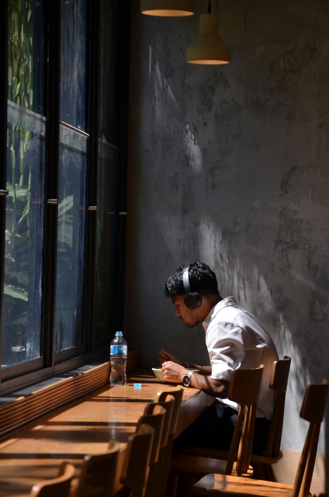 A man eating alone at a café counter with headphones on