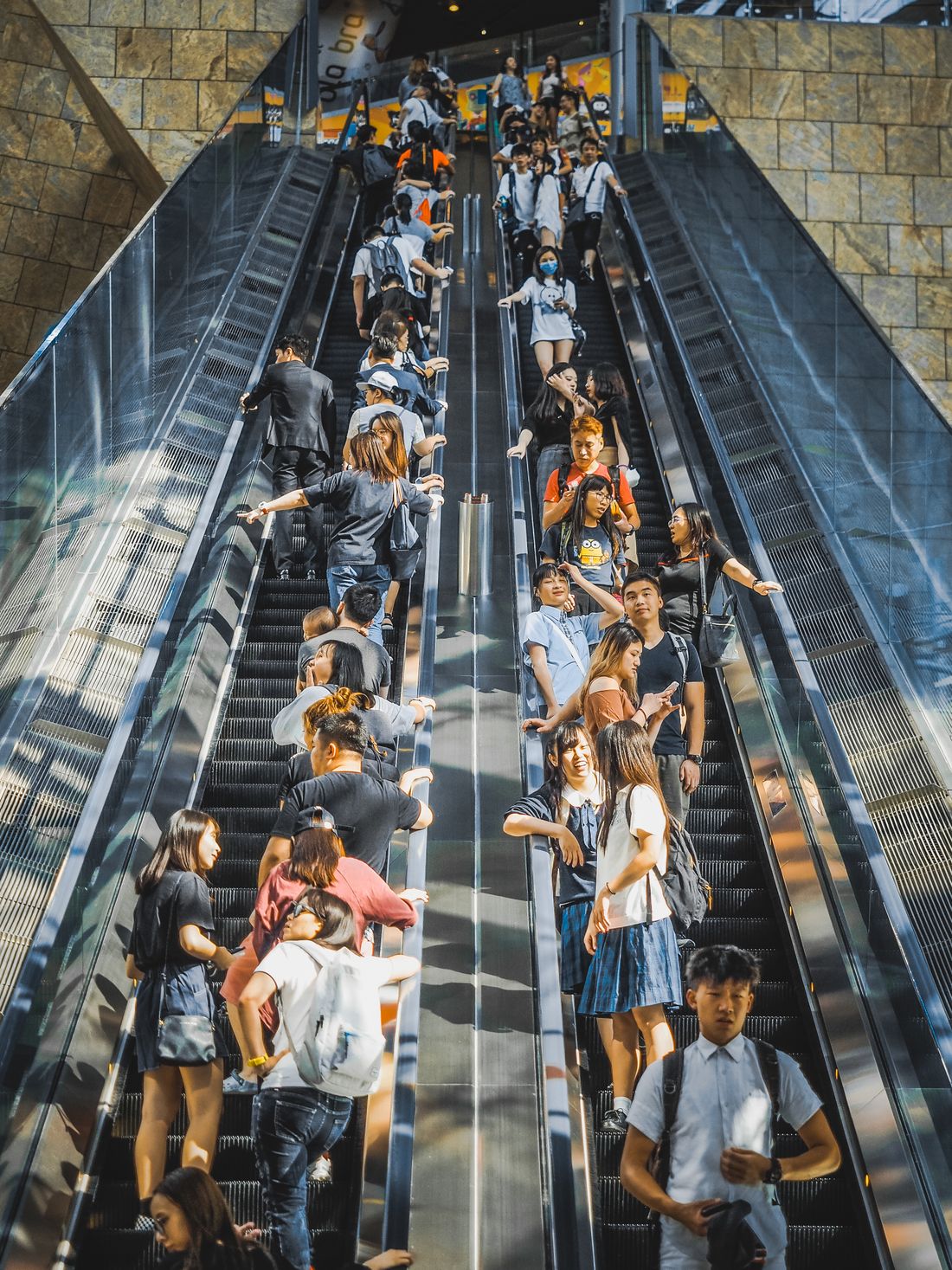 A crowd on mall escalators, everyone a stranger
